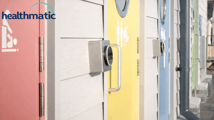 Close-up of individually coloured toilet cubicle doors — coral with a baby-change icon, yellow with a family icon, and blue — each with a keypad access lock.